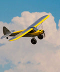 Carbon Cub S 2 1.3m RC Airplane BNF Basic With SAFE Technology for easy flying against a cloudy sky, showing yellow finish.