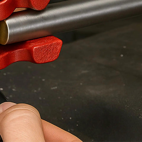 Close-up of the Tiny But Mighty 3 Inch Mini Handheld Vise With 1.25 Inch Jaws holding a metal rod, showcasing adjustable tension.