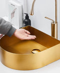 Top Shelf Stainless Steel Gold Vessel Sink, Semi Circular Above Counter Basin With Push Type Drain, showing hand above the sleek gold basin.