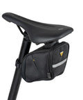 Aero Wedge Pack DX Medium Under Saddle Bag 0.9 L Expanding Capacity with QuickClick F25 Mount attached to bike seat with reflective strip.
