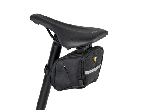 Aero Wedge Pack DX Medium Under Saddle Bag 0.9 L Expanding Capacity with QuickClick F25 Mount attached to bike seat with reflective strip.