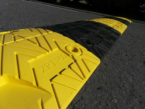 Eco XPT Speed Bump Kit With Cable Channel For Private Roads showing closeup of black and yellow modular sections on asphalt surface