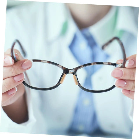 Person holding eyeglasses with 96 Piece Eyeglass Nose Pads Adhesive Cushions For Glasses Nonslip Comfort applied on the bridge.