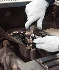 Side view of EZ RED BK706 battery terminal and wiper arm puller in use under the car hood with gloved hands.