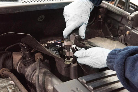 Side view of EZ RED BK706 battery terminal and wiper arm puller in use under the car hood with gloved hands.