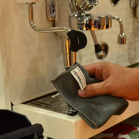 Person using Barista Cleaning Towel Set With Hook Pack Of 3 Microfiber Cloths For Espresso Machines Steam Wand And Coffee Bar Counter Maintenance Includes Two 30x30 Steam Wand Towels And One 30x60 Bar Towel With Clip For Your Go-To Cleaning Gear to wipe espresso machine.