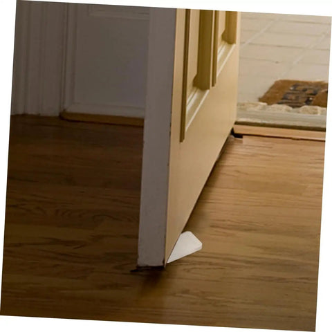 Clear Plastic Leveling Shims For Furniture Wobble Fix 32 Piece Wedge Set propping door corner on hardwood floor for stability.
