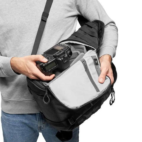 Person accessing ProTactic BP 300 AW II Mirrorless And DSLR Backpack with QuickShelf system, holding camera gear.