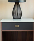 Modern lamp on wooden nightstand with sleek drawer