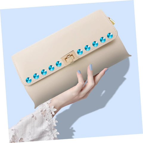 Front view of beige clutch bag with a row of turquoise metal studs along the flap and a gold clasp.