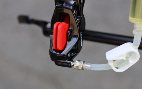 Close-up of bike brake caliper with fluid tube connected, part of Do It Yourself Friendly SRAM Hydraulic Brake Bleed Kit With 250ml DOT 5.1 Fluid Reusable 20ml Syringes Bleeding Edge Tool And Easy Video Guide For At Home Bike Brake Bleeding.