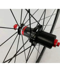 Close-up of rear hub on 700C road bike wheelset with carbon fiber hub, 40mm matte aluminum rim, quick release, stainless steel spokes.