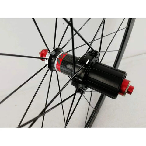 Close-up of rear hub on 700C road bike wheelset with carbon fiber hub, 40mm matte aluminum rim, quick release, stainless steel spokes.