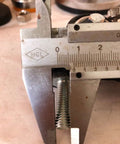 Close-up of a metal bolt being measured with a caliper, relating to Four M8x25mm PU Rotating Caster Set, Load Bearing 240kg Total Capacity.
