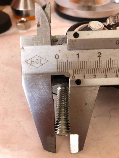 Close-up of a metal bolt being measured with a caliper, relating to Four M8x25mm PU Rotating Caster Set, Load Bearing 240kg Total Capacity.