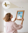 Person hanging a framed beach photo using Top Tier 80 Piece Picture Hanging Kit Featuring Assorted Bulletproof Metal Hooks And Heavy Duty Nails For Stress Free Wall Art Displays Supporting Up To 60 Pounds For Quick Do It Yourself Home Makeovers.