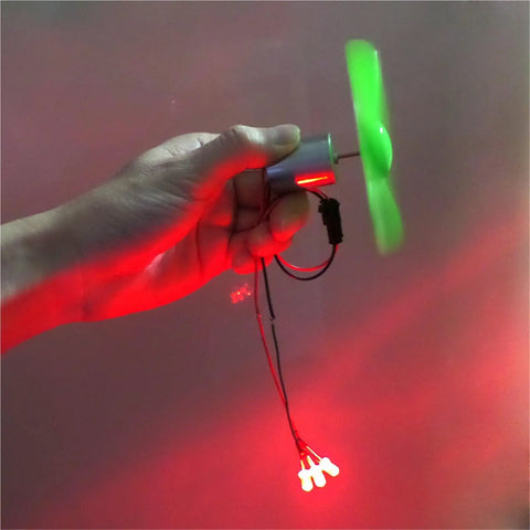 Hand holding Ten Pack Portable Mini Wind Power Generators Kit For Self Generation Outdoor Phone Charging, green blades spinning