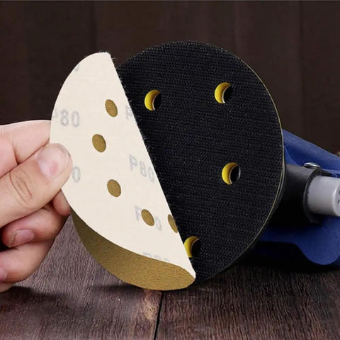 A hand holding a P80 5 inch hook and loop sanding disc, showing both sides for the Get The 150 Pack Of High Performance 5 Inch Hook And Loop Sanding Discs With Versatile Aluminum Oxide Grits For Smoother Orbital Sander Projects That Fly Off Clogging And Hold Tough.