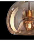 Close-up of Modern Dine Dining Room Pendant Lights Indoor Lighting Ceiling Lamp with amber glass shade and visible LED bulb.