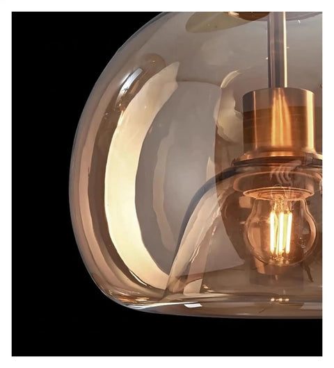 Close-up of Modern Dine Dining Room Pendant Lights Indoor Lighting Ceiling Lamp with amber glass shade and visible LED bulb.