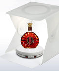 Rotating Display Stand With 10 Inch LED Light Turntable Base Black Spinning Platform showcasing a bottle in white light box
