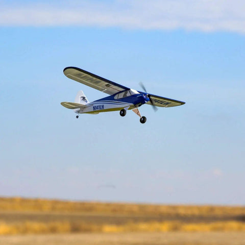 Blue and white compact foam Sport Cub S 2 RC Airplane BNF Basic with Safe Technology flying against clear sky.