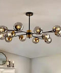 12 Light Large Sputnik Chandelier With Glass Globes In Matte Black And Gold installed in a modern living room
