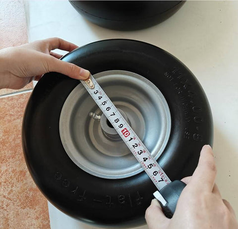 Person measuring Flat Free 11x4.00-5 Lawn Mower Tires With Wheel Kit Two Pack Universal Fit Rim Centered Hub Uses Bushings
