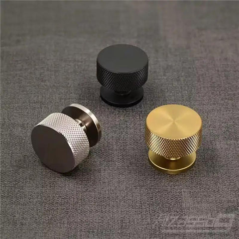 Kick Up Your Kitchen Game With These Solid Modern Brushed Brass Cabinet Knobs Perfect For Drawers And Cupboards Snag This Top Tier 10 Pack Hardware Set For A Fresh Upgrade. Three cabinet knobs in brushed brass, black, and silver finishes on a fabric background.