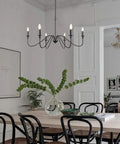 Six Light Wrought Iron Farmhouse Pendant Chandelier With Classic Candle Style For Kitchen Island Dining Room And Living Room Black Matte Finish Easy Install And Low Maintenance hanging over dining area.