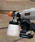 Cordless 20V Paint Sprayer Gun With Dual Batteries, HVLP Sprayer, Adjustable Valve Knob in use against wooden surface
