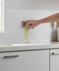 Cleaning grease from peel and stick self adhesive wallpaper roll subtle gray linen texture waterproof vinyl in a kitchen setting.
