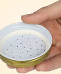 Hand holding perforated metal lid from Bee Entrance Feeder For Beehives 8 Pack Perforated Metal Mason Jar Lids Waterers