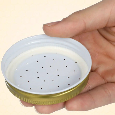 Hand holding perforated metal lid from Bee Entrance Feeder For Beehives 8 Pack Perforated Metal Mason Jar Lids Waterers