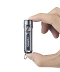 Hand holding Ti2 EDC Flashlight Tiny But Mighty Pocket Size Keychain Light With 120 Lumen Output Powered By AAA Battery Ultra Lightweight Waterproof And Shockproof For Everyday Carry Black