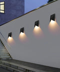 Four 10W 3000K Waterproof IP65 Indoor Outdoor Wall Sconce LED Light Fixture illuminating a modern exterior wall at dusk.