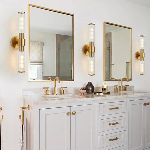 Modern bathroom with brass fixtures and white vanity, mirrors flanked by wall lights.