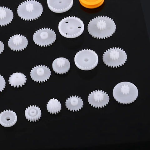 Grab This Awesome DIY Robot Gears And Pulley Belt Kit With 64 Kinds Of Wearable Plastic Parts Perfect For Tech Models, Car Robots, And Cool Motor Projects You Can Build Your Own Stuff With Today white plastic gears on black background
