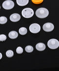 Totally Awesome 64 Kinds Plastic Gears Pulley Belt Kits For Robot Motor Toys Perfect For Engineering And Model Making Projects Great Stuff For DIY Builds, white plastic gears on black background
