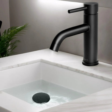 Matte black stainless steel bathroom faucet with single handle and pop up drain stopper, modern design on white countertop