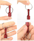Hand holding a red metal keychain from the 10 Pack Keychain Magnets for Gold and Jewelry Testing - Neodymium Pocket Magnetic Tester Kit.