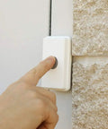 Hand pressing button on Long Range Wireless Doorbell Kit For Home And Biz With Dual Function Transmitter That Acts As Push Button