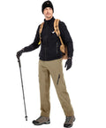 Man wearing mens waterproof hiking pants with fleece lined insulated soft shell for winter, standing with backpack and hiking stick.