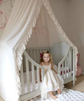 Tot Friendly Cozy Kids Bed Canopy With Lace Chiffon Netting And Pom Poms Dreamy Princess Fairy Tent installed on a crib