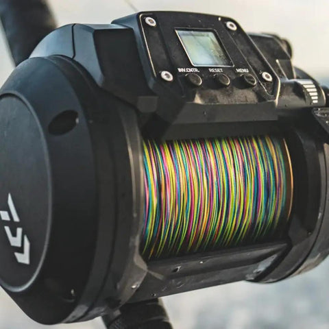 Close-up of Tanacom 1200 Power Assist Electric Reel for Deep Drop and Kite Fishing in Saltwater with multicolor fishing line.