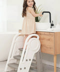 Hassle Free Three Step Bathroom Stool For Toddlers With Adjustable Handlebars, foldable design, child using it at the sink.