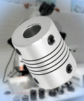 Aluminum 10mm–10mm flexible beam coupling, 25mm long, four set-screw holes, close-up view