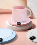 Slick Aluminum Coffee Cup Warmer With Smart Touch Controls And Automatic Shutoff keeps drinks hot at 55 degrees on a pastel desk.