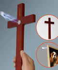 Wooden cross-shaped device emitting electric light on wall with photo of a dog, illustrating functionality.