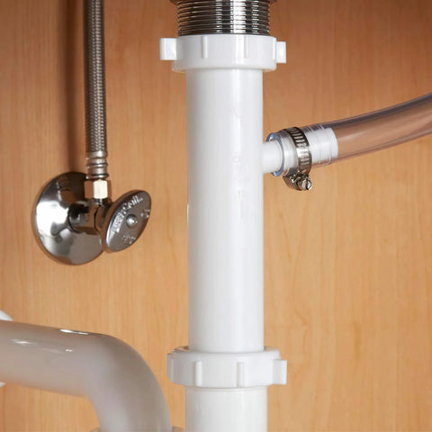 Worm-gear stainless steel hose clamp securing a clear hose to a white PVC drain pipe under a sink